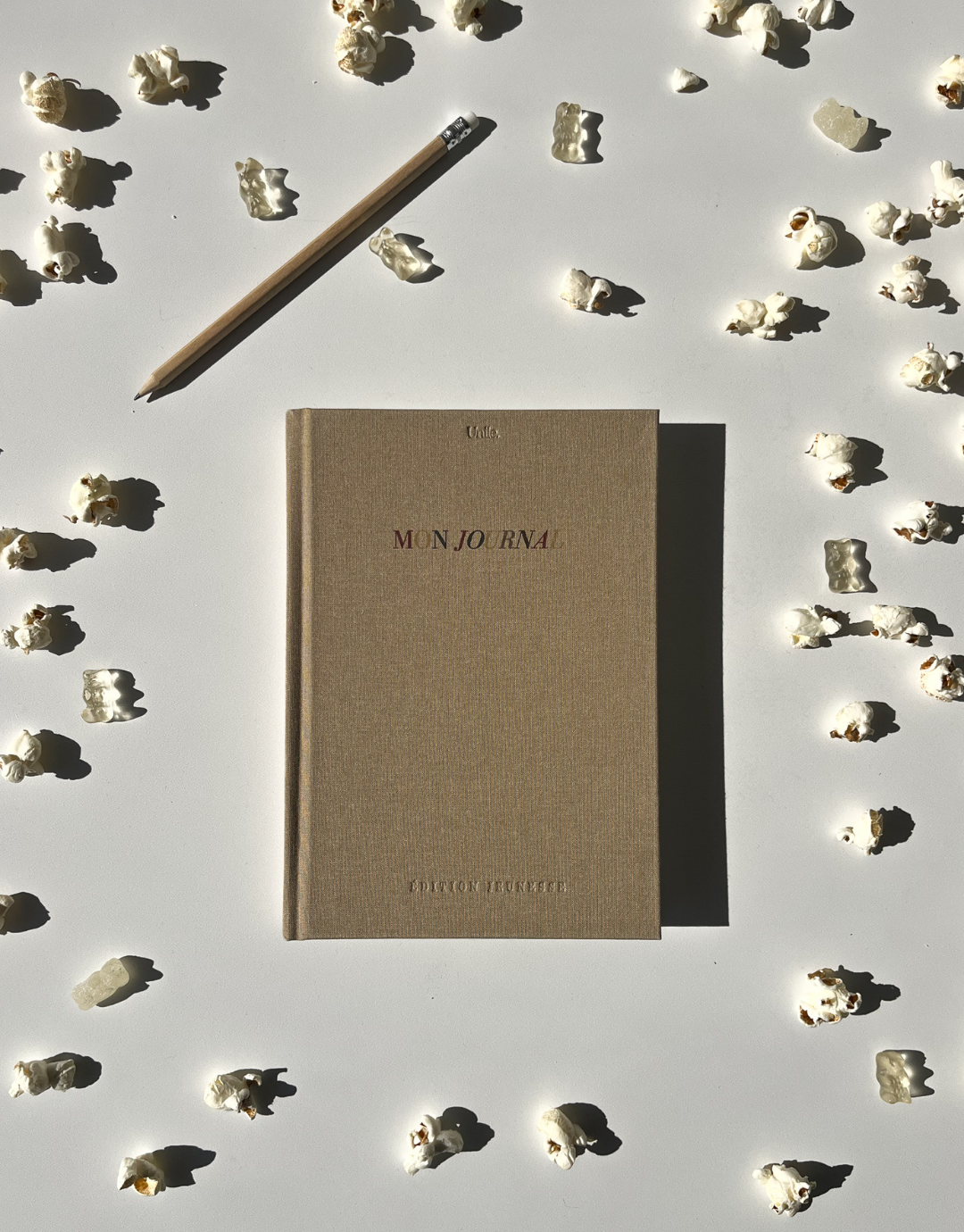 Le journal pour enfants Unile, entouré de bonbons et de pop-corn créant une ambiance aesthetic et graphique.