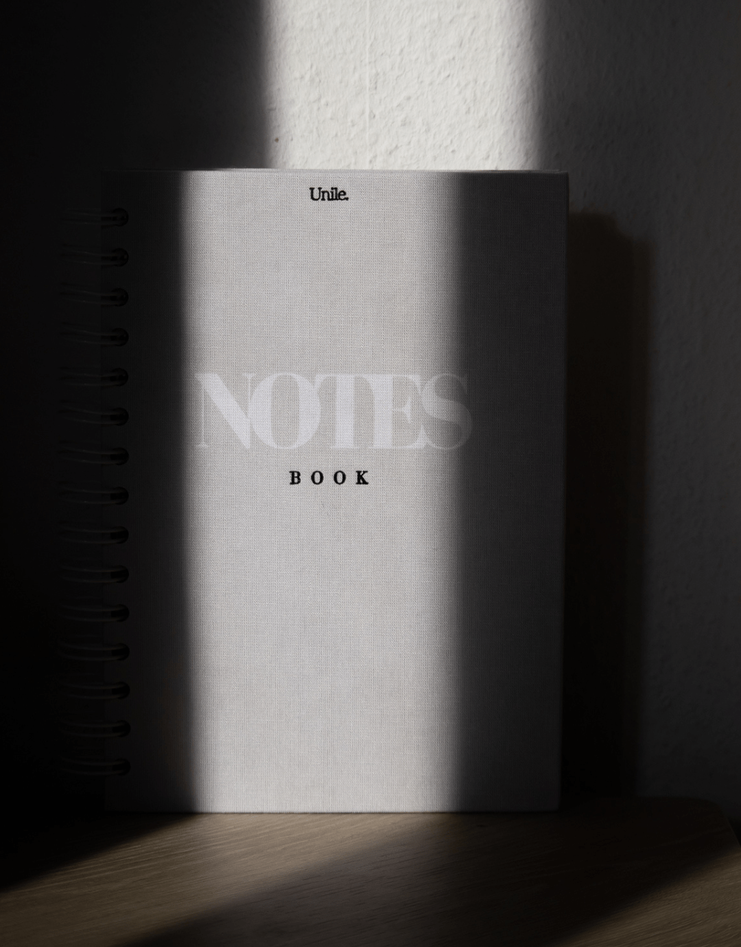 LE notebook - unile.selfcare couverture du notebook posé de face avec jeux d'ombres et de lumière