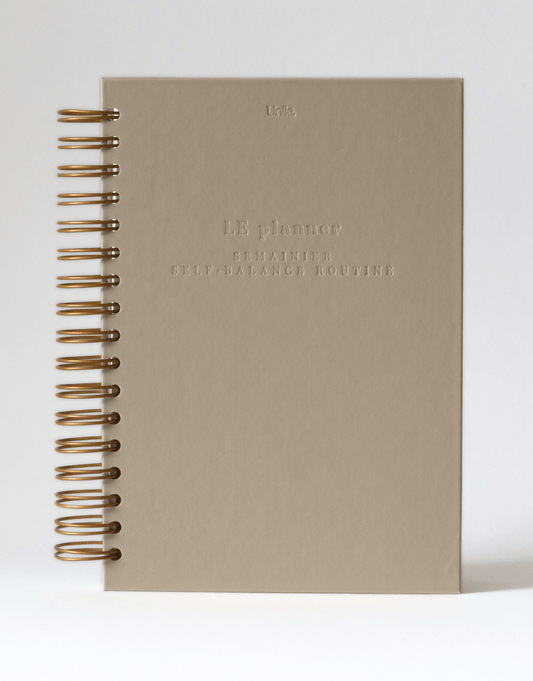 LE planner beige honey Unile Self-care planner avec grandes spirales dorées et lettres gravées.