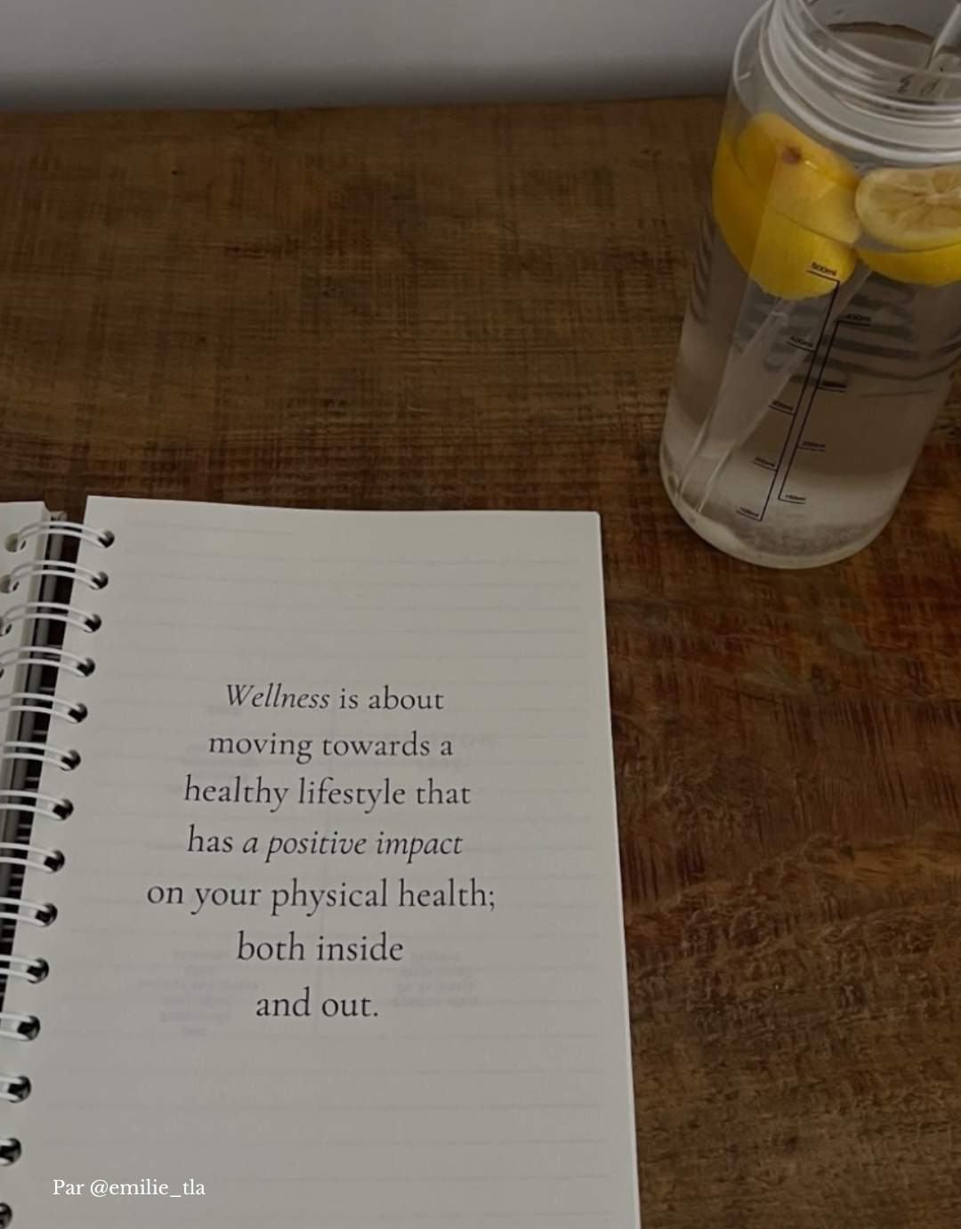 Page de citation du notebook Unile Selfcare posé sur une table en bois à côté d'un verre d'eau citronnée par Emilie Wellness Culture.