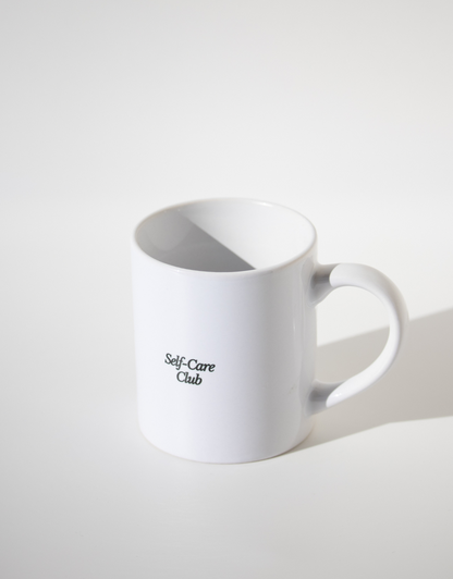 LA tasse - unile.selfcare tasse blanche lettrage noir Self-care Club sur fond blanc avec jeu d'ombres.